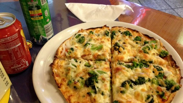 Brokkoli Pizza neben zwei Limo Dosen