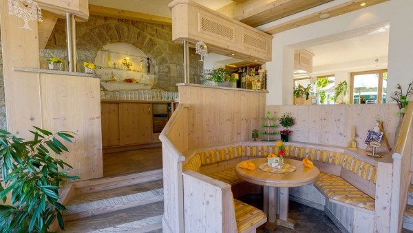 Sitzecke und Bar komplett aus Holz, gelbe Stilelemente, eine Pflanze und Marmor-Fußboden
