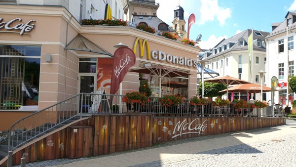 McDonald's Plauen, Eingang Klosterstraße. Schriftzug, bunte Blumen und Sonnenschirme