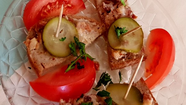 Speckfett-Brot auf Glasteller mit Gewürzgurke, Tomate und Petersilie, aufgespießt in Holzspießen