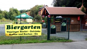 Gelber Banner aum Zaun mit der Aufschrift: Biergarten Thüringer Roster, Getränke, Kaffee und Kuchen, Eis