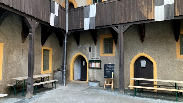 Innenhof einer Burg. Geländer aus Holz. Schwarz weiße Fahnen hängen herab. Bierzreltgarnituren stehen bereit.