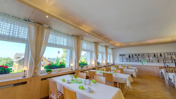 Restaurant. Viele Tische in Reihe neben Fenster. Alle Tische sind sauber und gedeckt. Große weiße Decke.