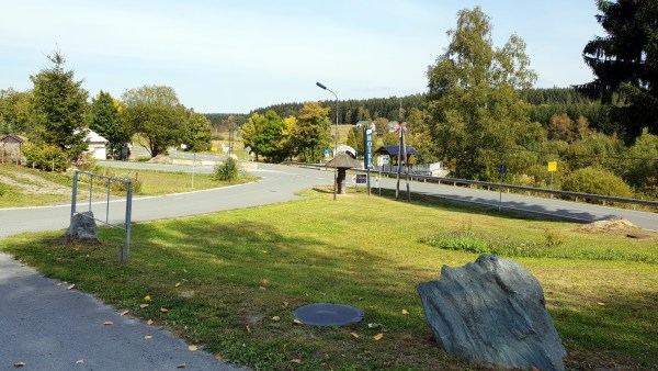 Straße mit Einfahrt zwischen Wiese und Bäumen