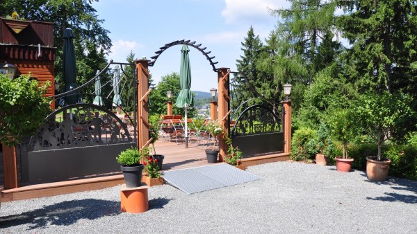 Eingang zum Biergarten mit erzgebirgischen Schibbögen unter Bäumen mit schöner Aussicht