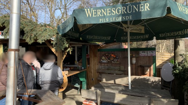 Holztische, Holzstühle, Holzwände. Biergarten mit Wernesgrüner-Sonnenschirm