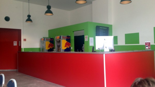 Rote Bar, dahinter grüne Zwischenwände, Red-Bull-Kühlschränke