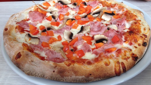 Schinken-Pizza mit Pilzen, Tomatensoße und Käse auf Teller