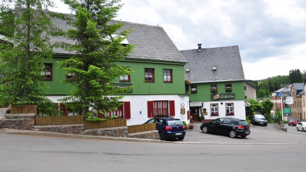 Postillion, Grünes Haus (Außenansicht) hinter Tannen mit Parkplatz an Kreuzung