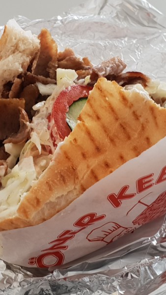 Döner Kebab in Papier auf Alu-Folie zum Anbeißen, leicht geöffnet