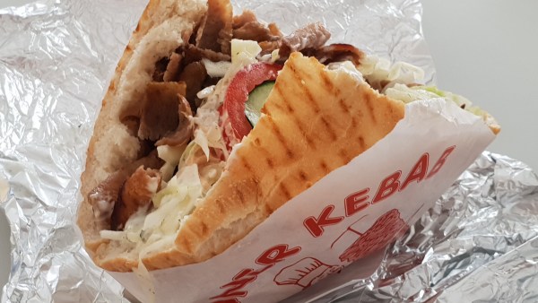 Döner Kebab in Papier auf Alu-Folie zum Anbeißen, leicht geöffnet