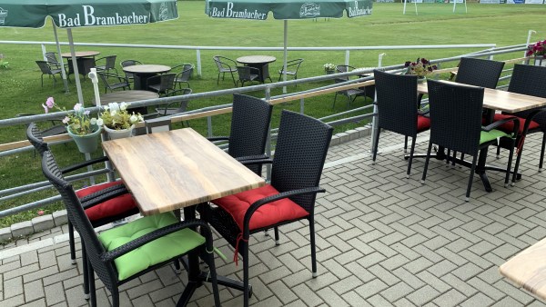 Tische und Stühle mit Sonnenschirmen am Sportplatz (Wiese)