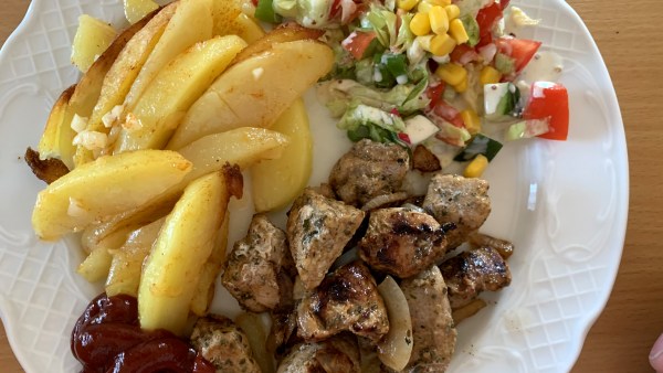 Fleisch, Kartoffelstücke, Ketchup und Salatbeilage