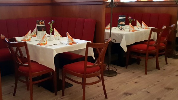 Rote Sitzbank und Stühle und Tische mit weißer Tischdecke