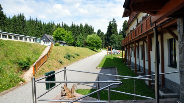 Metallgeländer vor Weg zwischen Hang und Haus im Wald